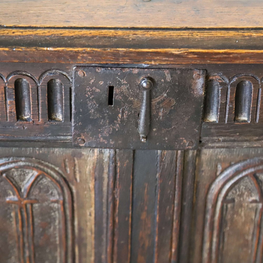 A dark oak coffer featuring four hand-carved Gothic arch panels, a fluted frieze, and a sturdy four-panel hinged lid. View V