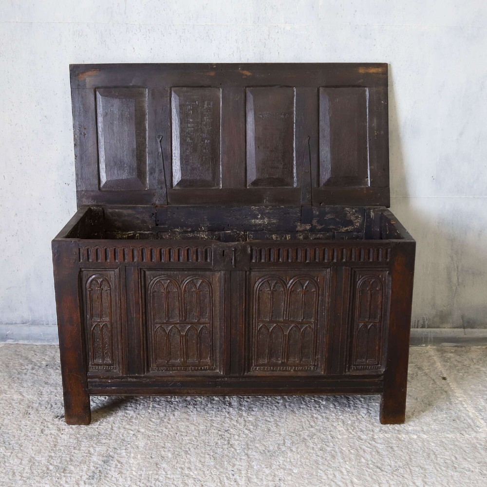 A dark oak coffer featuring four hand-carved Gothic arch panels, a fluted frieze, and a sturdy four-panel hinged lid. View VIII