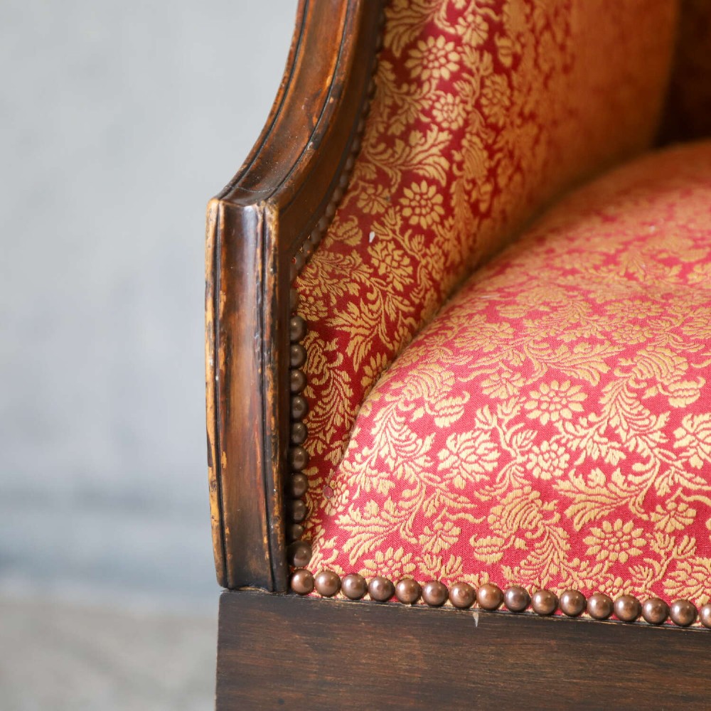 A mid-19th-century high-back wing armchair upholstered in red and gold patterned fabric with carved dark timber legs on casters. View VIII