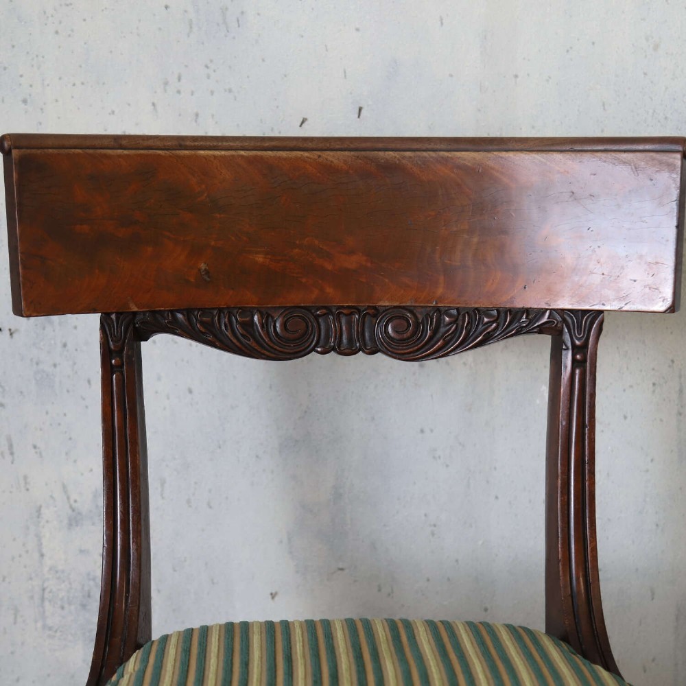 A pair of William IV mahogany side chairs featuring curved top rails with relief carving, fluted front legs, and seats upholstered in green and gold striped fabric. View V