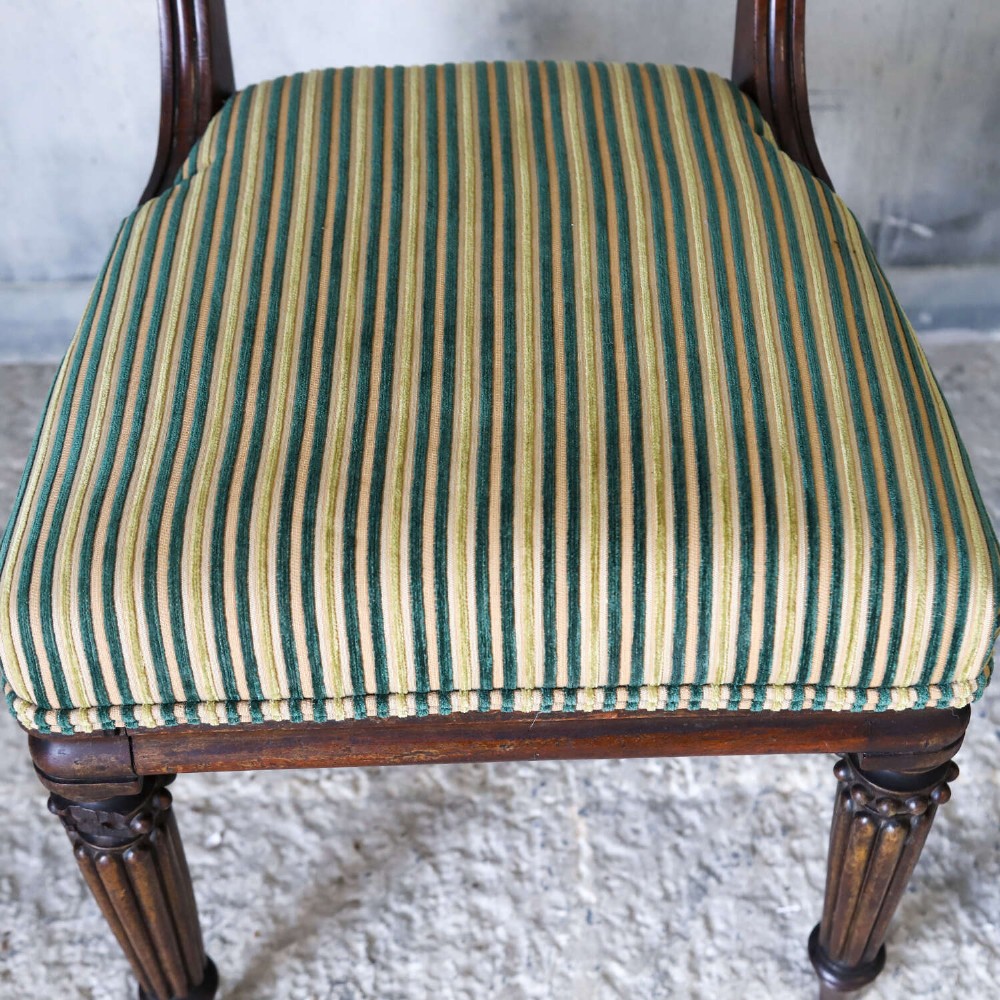 A pair of William IV mahogany side chairs featuring curved top rails with relief carving, fluted front legs, and seats upholstered in green and gold striped fabric. View VIII