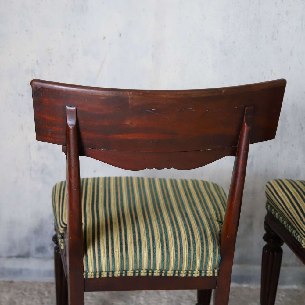A pair of William IV mahogany side chairs featuring curved top rails with relief carving, fluted front legs, and seats upholstered in green and gold striped fabric. View XII