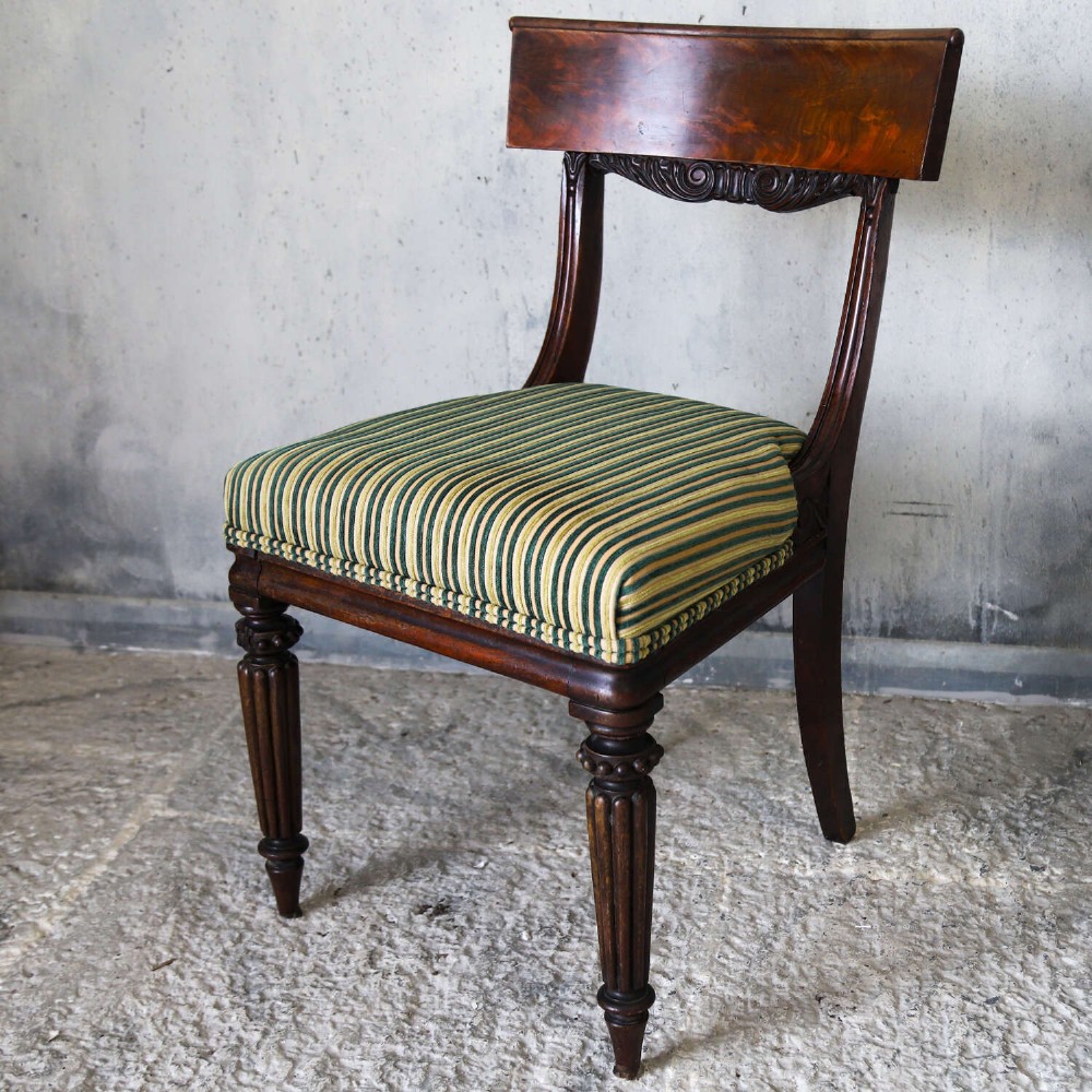 A pair of William IV mahogany side chairs featuring curved top rails with relief carving, fluted front legs, and seats upholstered in green and gold striped fabric. View XIII