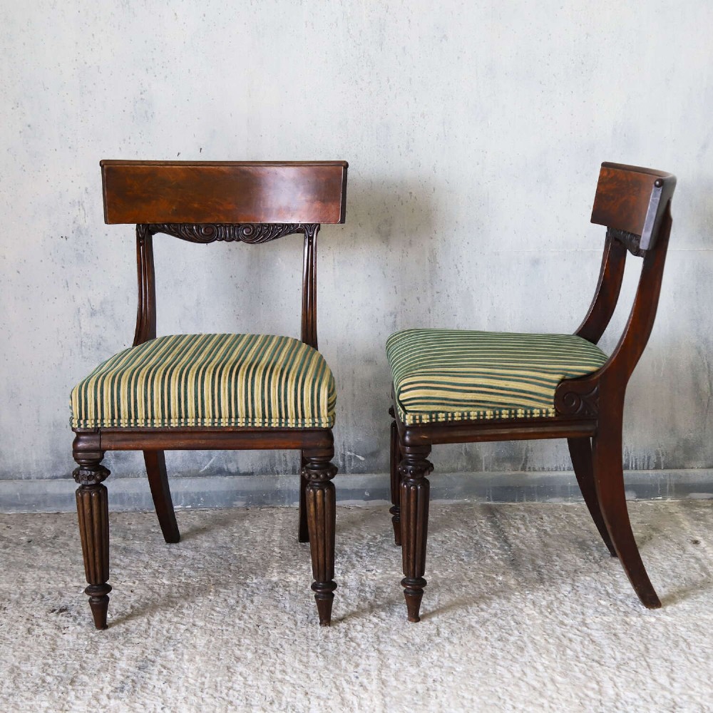 A pair of William IV mahogany side chairs featuring curved top rails with relief carving, fluted front legs, and seats upholstered in green and gold striped fabric. View XIV