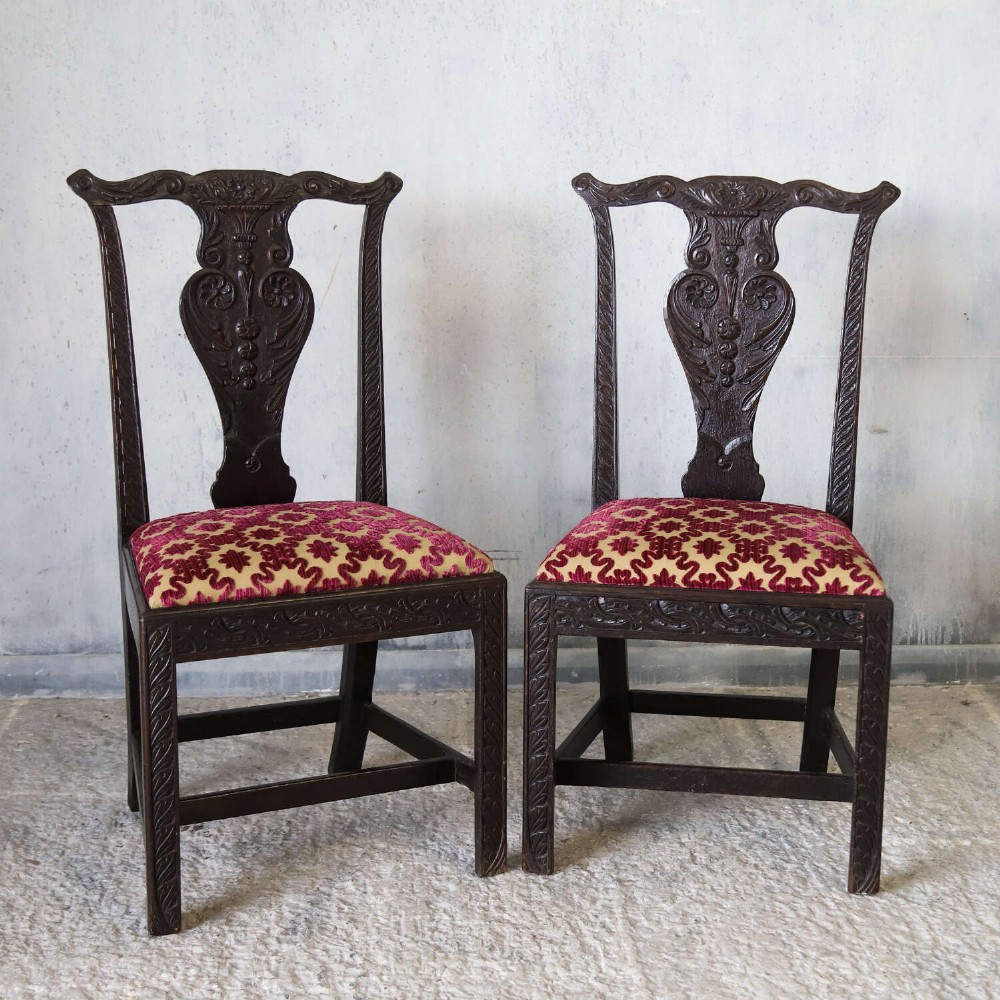 A pair of dark carved oak side chairs with vasiform splats and seats upholstered in red and gold patterned velvet. View II