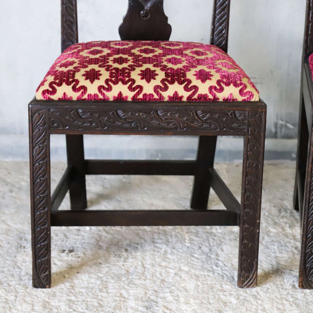A pair of dark carved oak side chairs with vasiform splats and seats upholstered in red and gold patterned velvet. View V