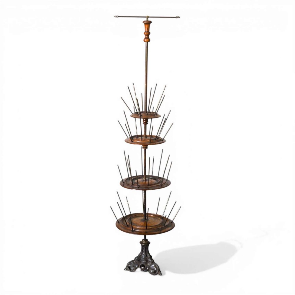 A four-tiered Victorian cotton reel display tree featuring circular wooden tiers with vertical metal spindles set on a cast iron base.