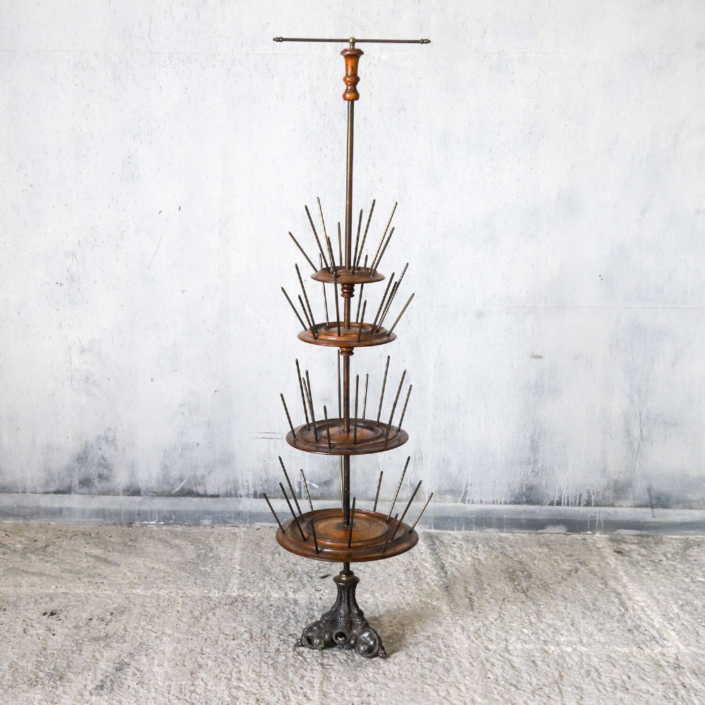 A four-tiered Victorian cotton reel display tree featuring circular wooden tiers with vertical metal spindles set on a cast iron base. View II