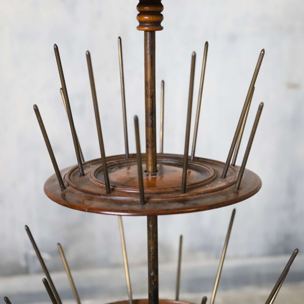A four-tiered Victorian cotton reel display tree featuring circular wooden tiers with vertical metal spindles set on a cast iron base. View VI