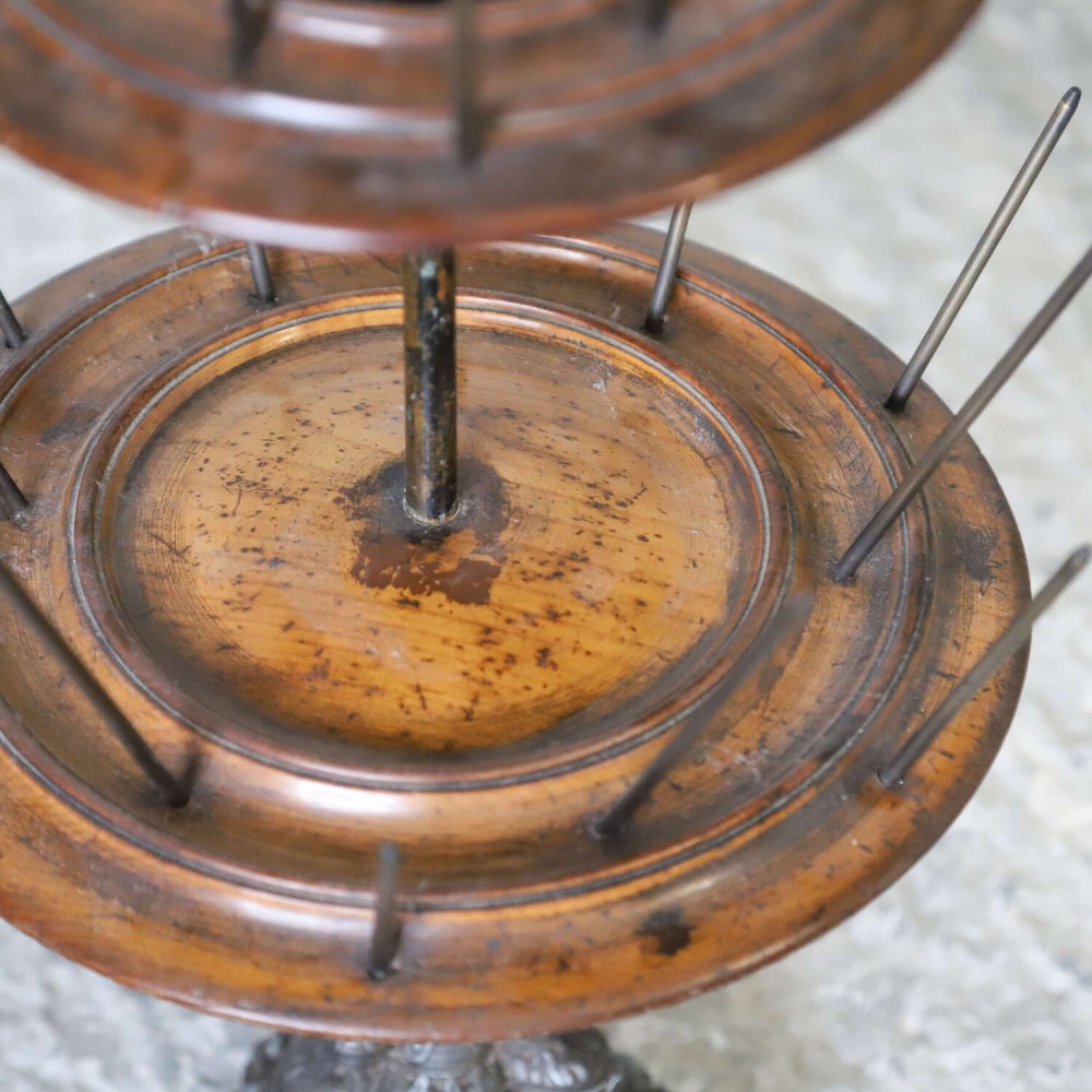 A four-tiered Victorian cotton reel display tree featuring circular wooden tiers with vertical metal spindles set on a cast iron base. View IX