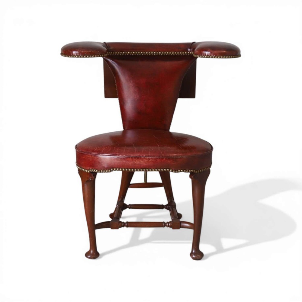 A late Victorian Sheraton style reading chair upholstered in burgundy red leather with brass studding and mahogany legs.