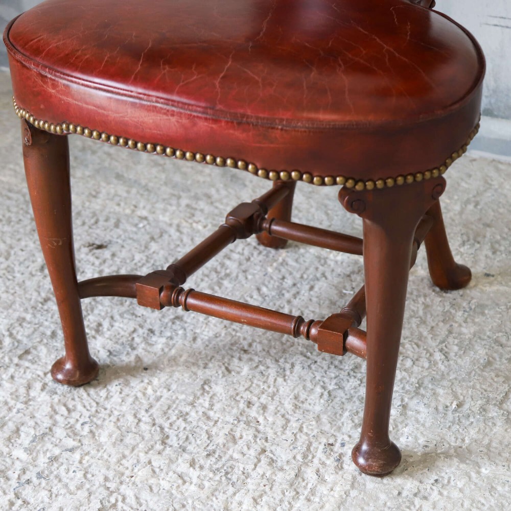 A late Victorian Sheraton style reading chair upholstered in burgundy red leather with brass studding and mahogany legs. View V