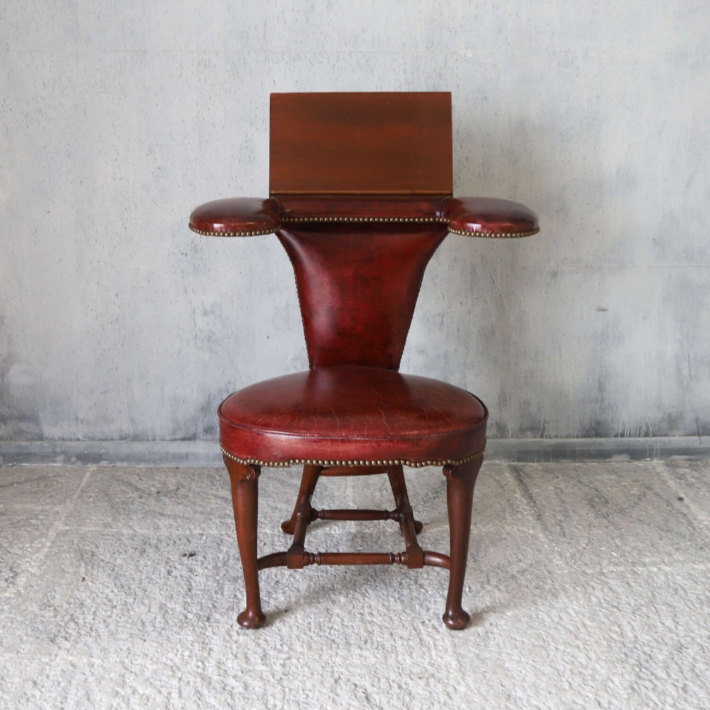 A late Victorian Sheraton style reading chair upholstered in burgundy red leather with brass studding and mahogany legs. View VI