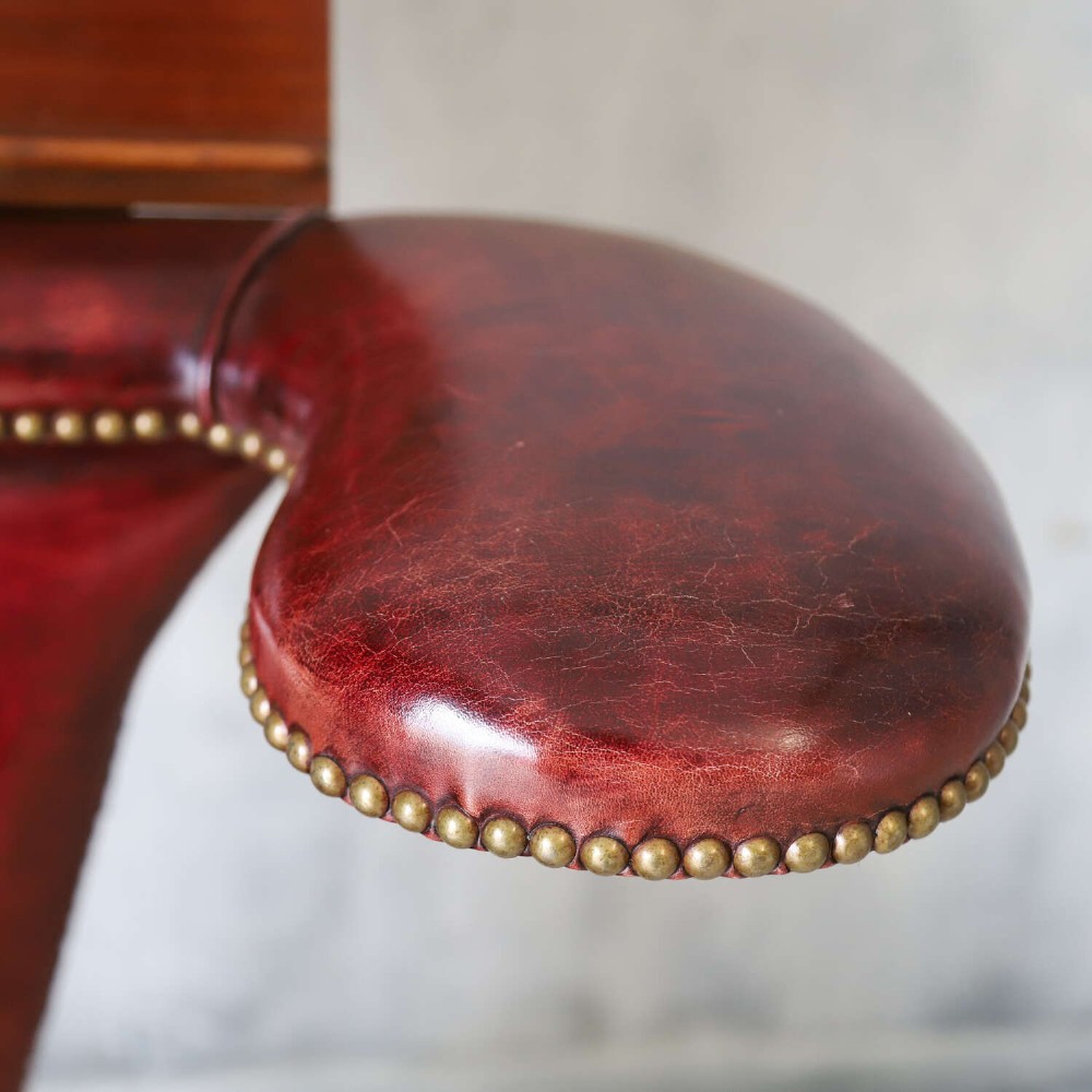 A late Victorian Sheraton style reading chair upholstered in burgundy red leather with brass studding and mahogany legs. View VIII