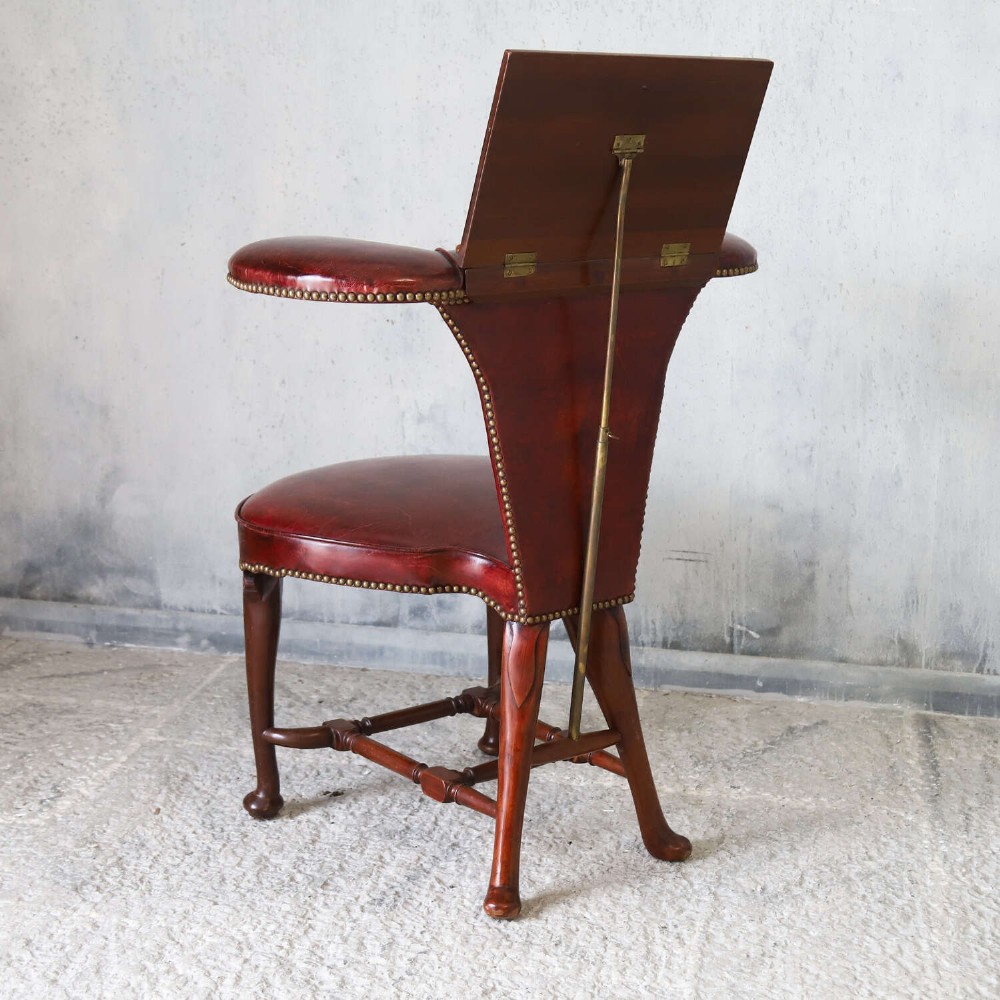 A late Victorian Sheraton style reading chair upholstered in burgundy red leather with brass studding and mahogany legs. View X