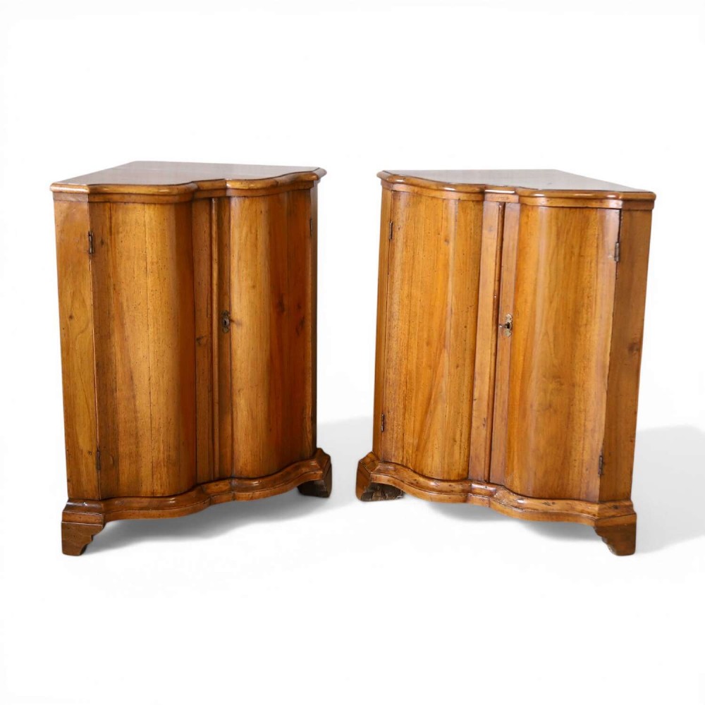 A matching pair of 18th-century Italian walnut corner cupboards with serpentine fronts and brass keyhole escutcheons.