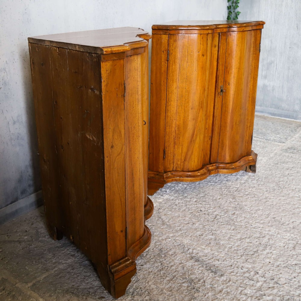 A matching pair of 18th-century Italian walnut corner cupboards with serpentine fronts and brass keyhole escutcheons. View V