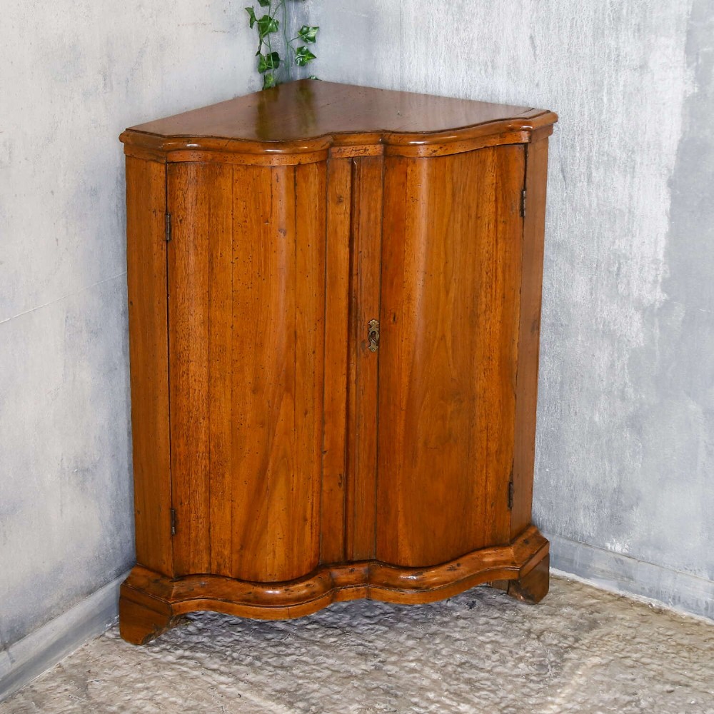 A matching pair of 18th-century Italian walnut corner cupboards with serpentine fronts and brass keyhole escutcheons. View XIII