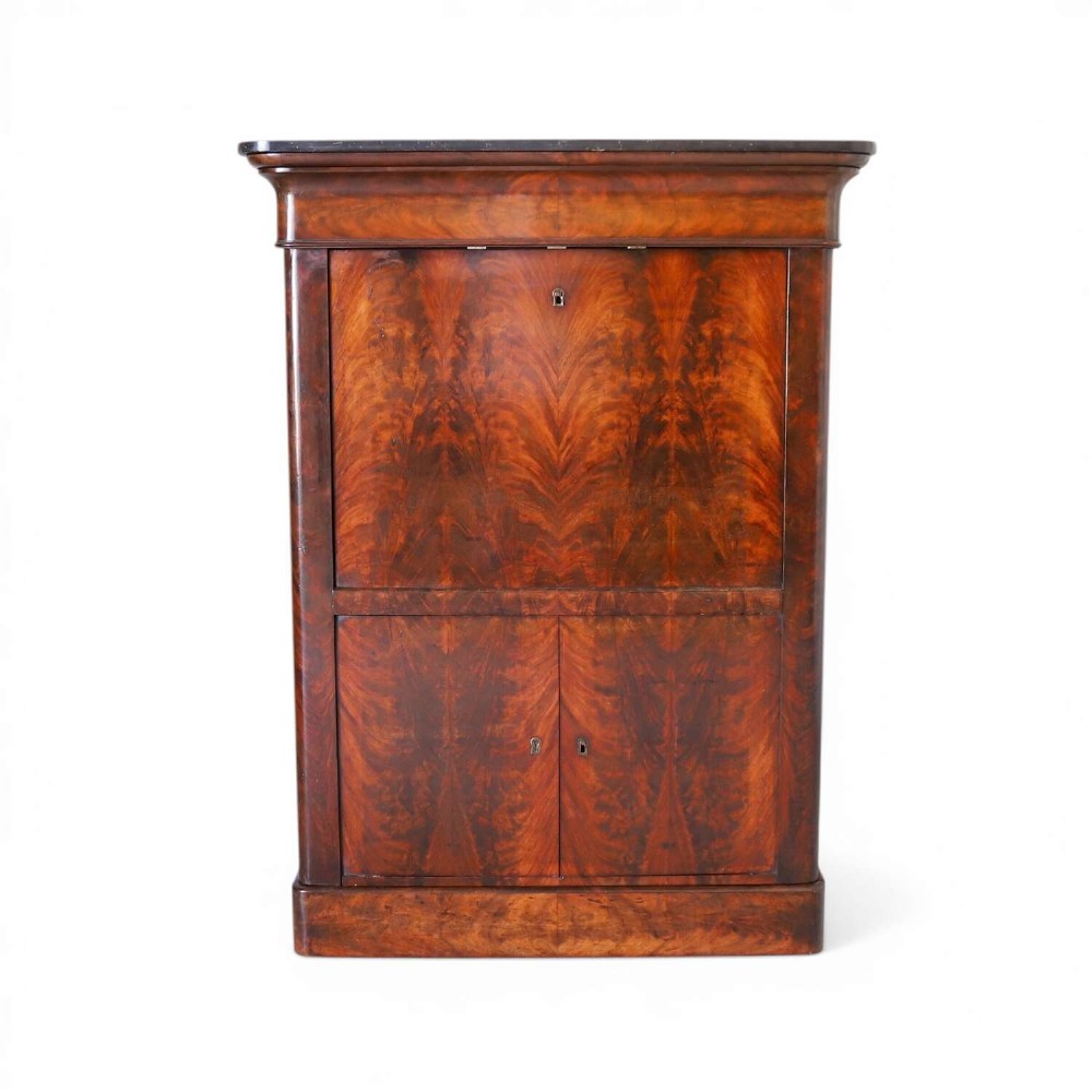 A 19th-century French secretaire a abattant featuring flame mahogany veneers, a dark marble top slab, an upper drop-front writing panel, and lower cupboard doors.