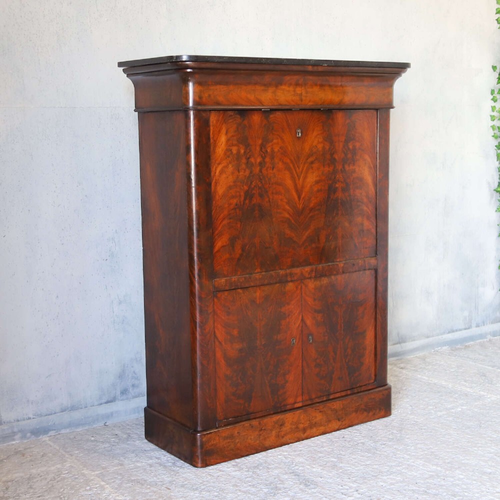 A 19th-century French secretaire a abattant featuring flame mahogany veneers, a dark marble top slab, an upper drop-front writing panel, and lower cupboard doors. View II