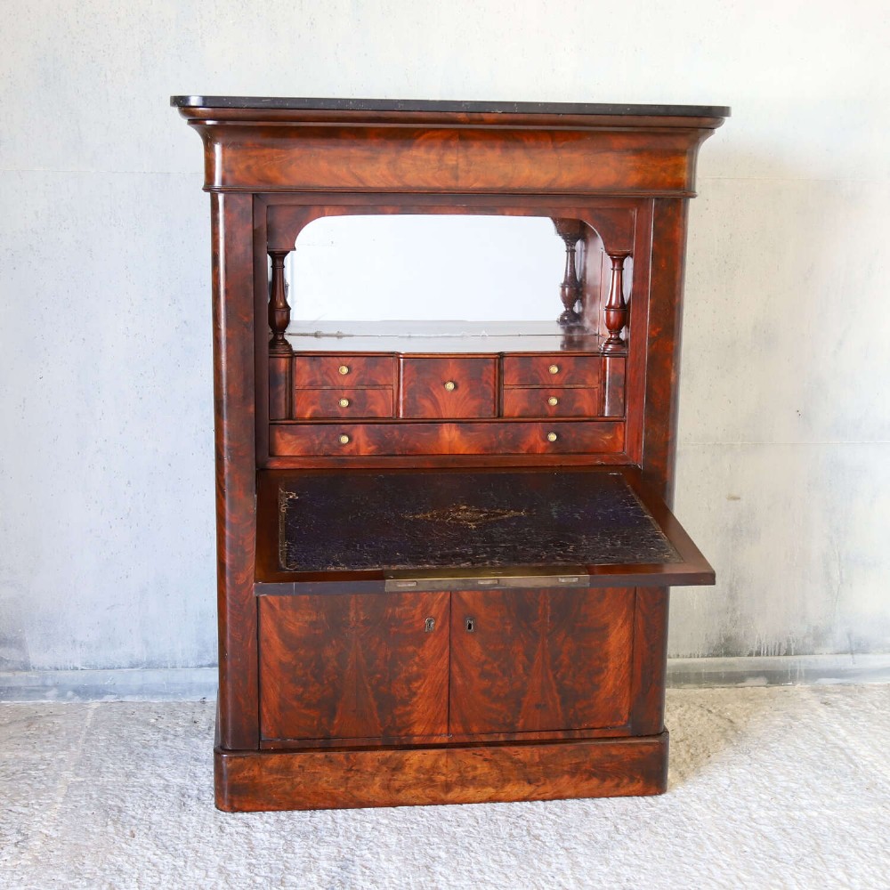 A 19th-century French secretaire a abattant featuring flame mahogany veneers, a dark marble top slab, an upper drop-front writing panel, and lower cupboard doors. View V
