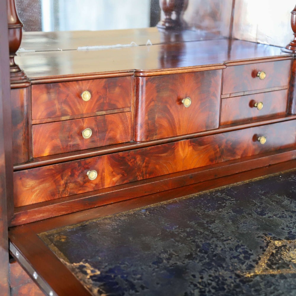 A 19th-century French secretaire a abattant featuring flame mahogany veneers, a dark marble top slab, an upper drop-front writing panel, and lower cupboard doors. View VI