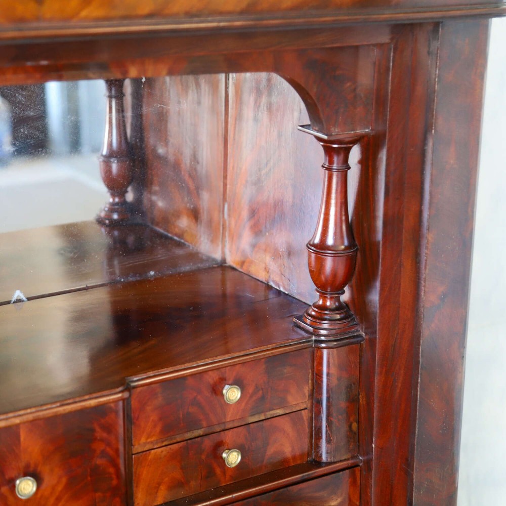 A 19th-century French secretaire a abattant featuring flame mahogany veneers, a dark marble top slab, an upper drop-front writing panel, and lower cupboard doors. View VII