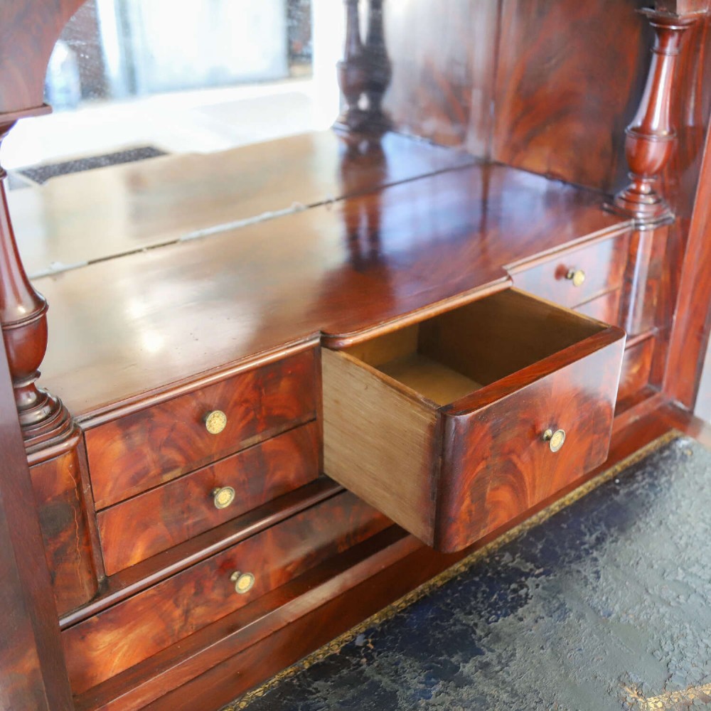 A 19th-century French secretaire a abattant featuring flame mahogany veneers, a dark marble top slab, an upper drop-front writing panel, and lower cupboard doors. View X