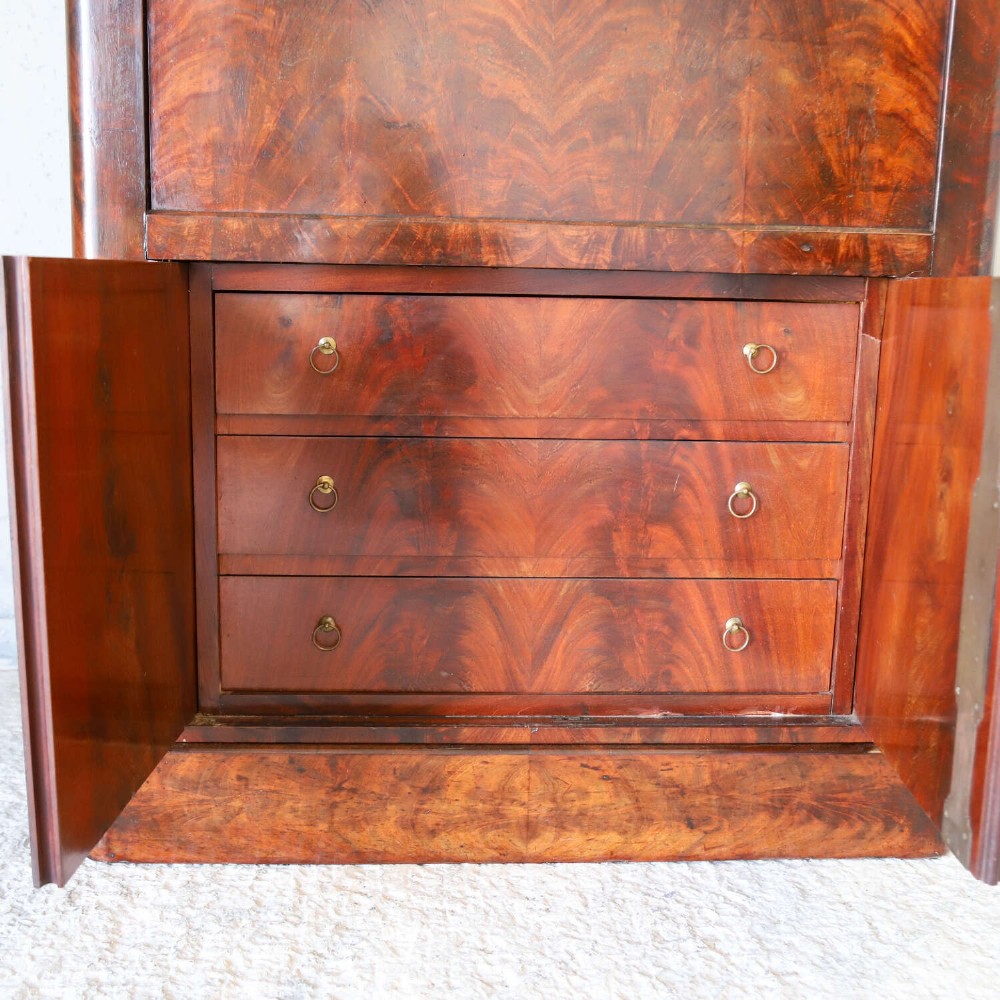 A 19th-century French secretaire a abattant featuring flame mahogany veneers, a dark marble top slab, an upper drop-front writing panel, and lower cupboard doors. View XIII