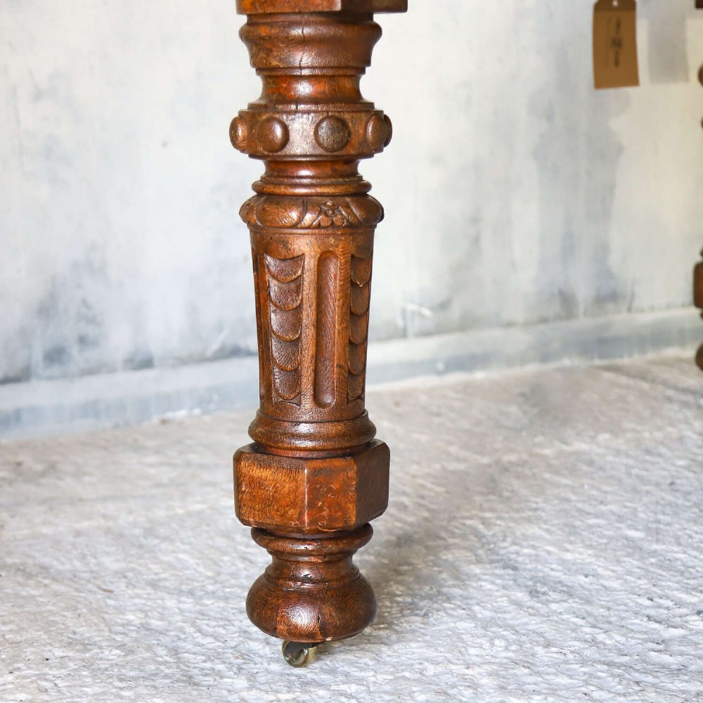 A 19th-century English oak Gothic Revival library table featuring an inset leather top and carved turned legs on brass castors. View IX