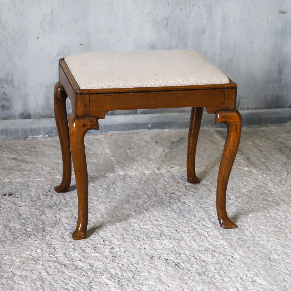 An early eighteenth-century George I walnut stool featuring four shaped cabriole legs and a cream upholstered drop-in seat. View II