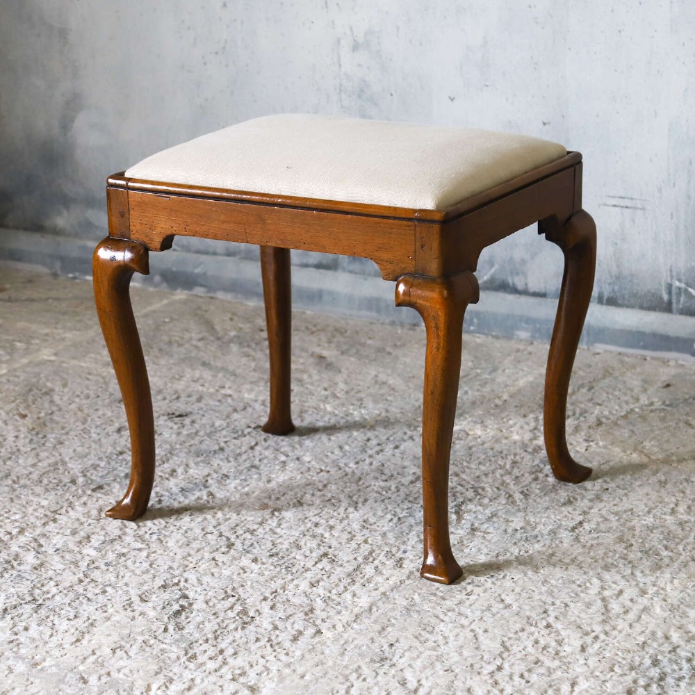 An early eighteenth-century George I walnut stool featuring four shaped cabriole legs and a cream upholstered drop-in seat. View IV