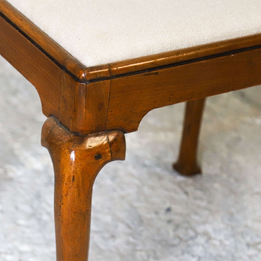 An early eighteenth-century George I walnut stool featuring four shaped cabriole legs and a cream upholstered drop-in seat. View VIII