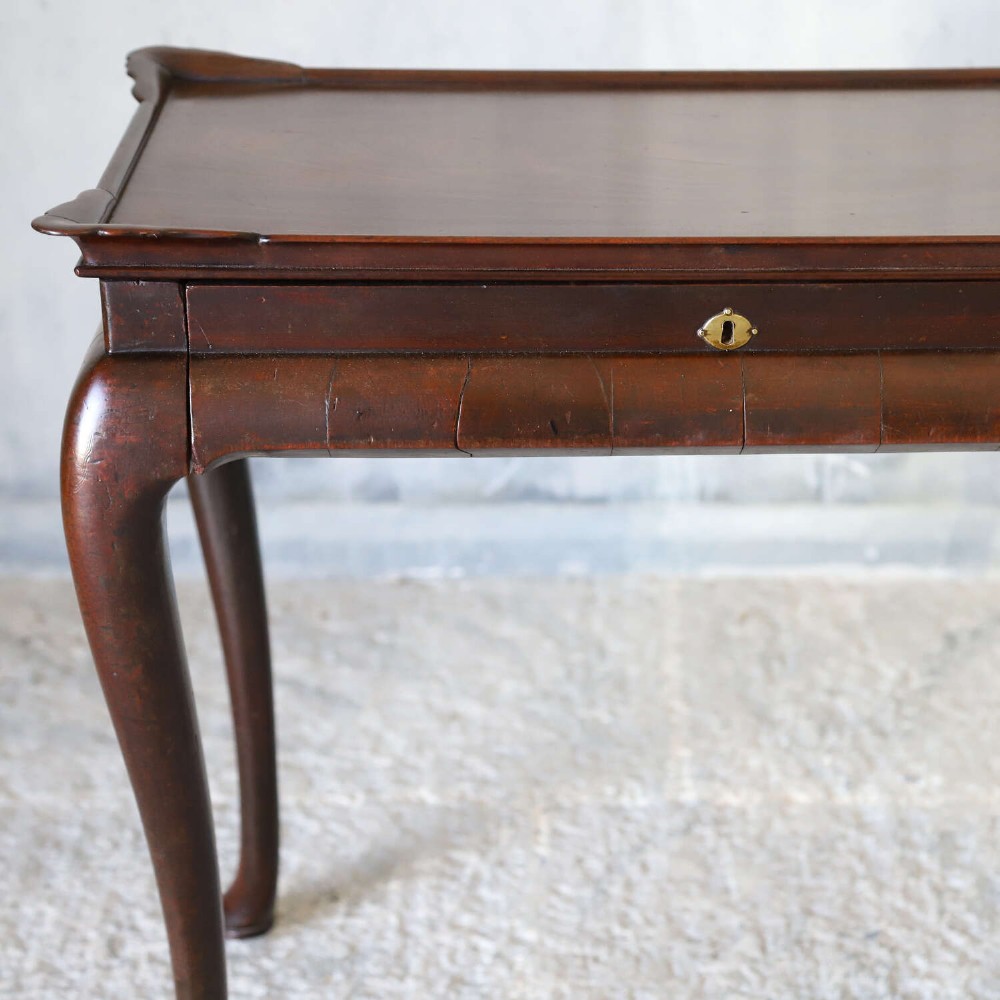 An early Georgian dark Cuban mahogany silver table featuring a raised tray top rim, single drawer with brass escutcheon, and slender cabriole legs terminating in pad feet. View III