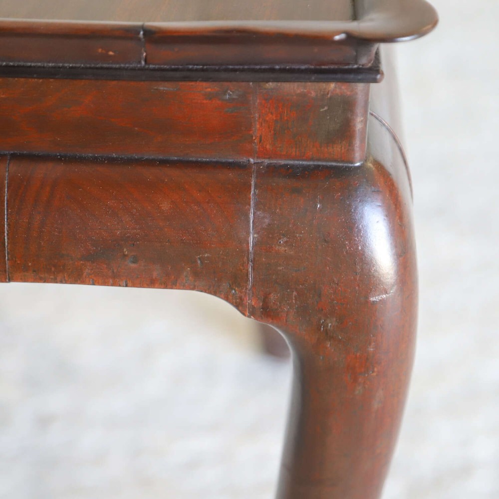 An early Georgian dark Cuban mahogany silver table featuring a raised tray top rim, single drawer with brass escutcheon, and slender cabriole legs terminating in pad feet. View X
