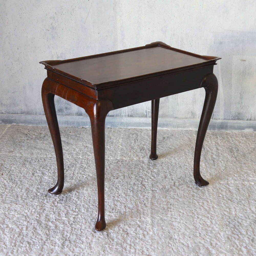 An early Georgian dark Cuban mahogany silver table featuring a raised tray top rim, single drawer with brass escutcheon, and slender cabriole legs terminating in pad feet. View XIV