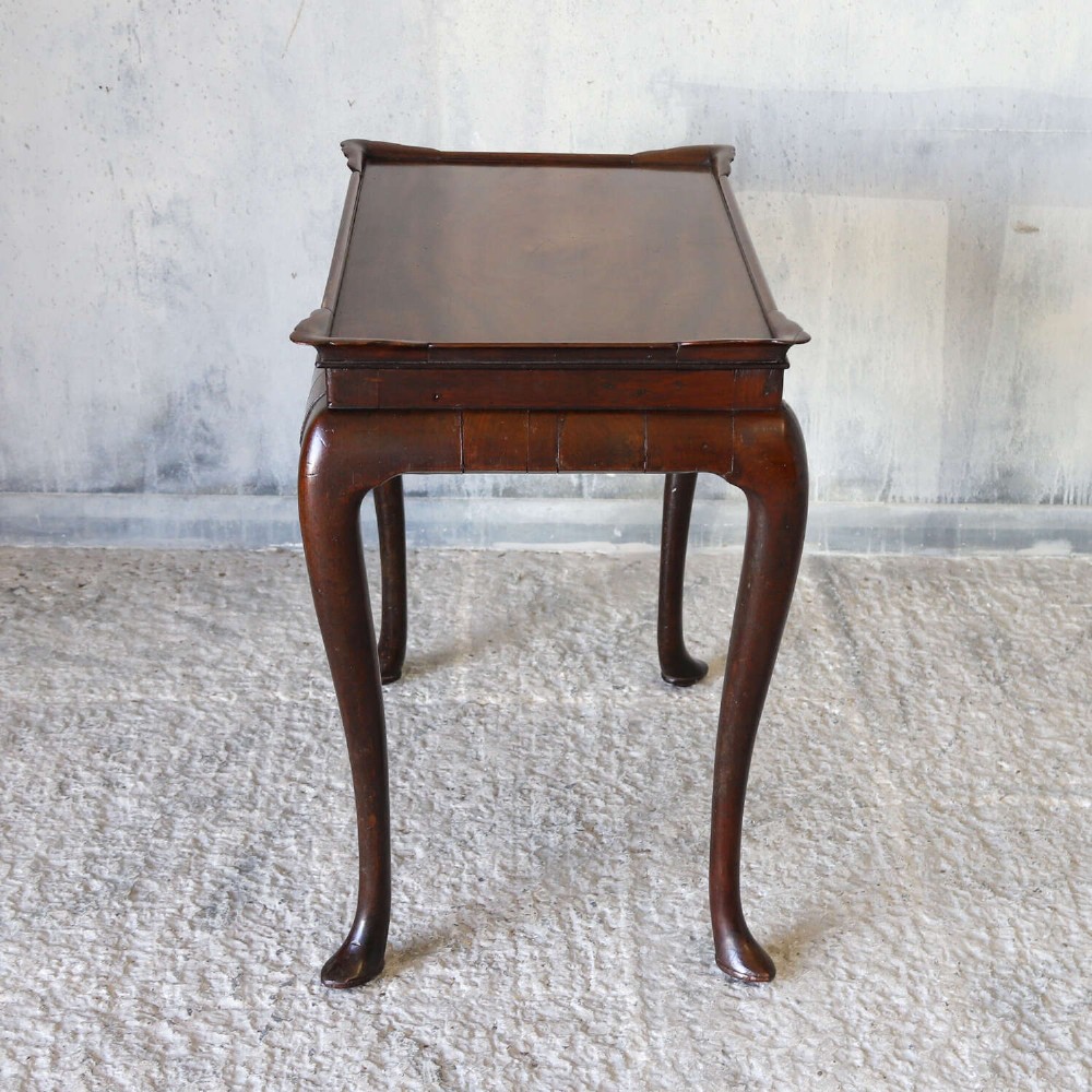 An early Georgian dark Cuban mahogany silver table featuring a raised tray top rim, single drawer with brass escutcheon, and slender cabriole legs terminating in pad feet. View XV