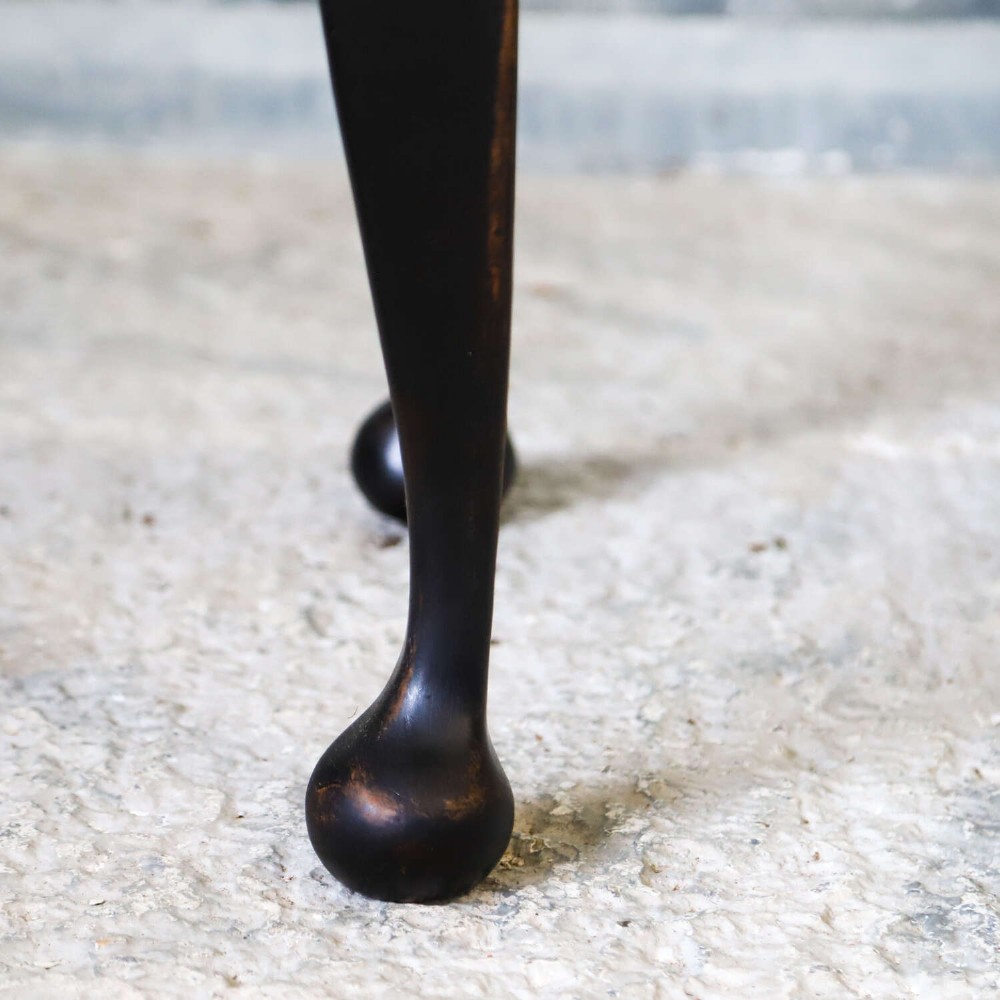 An Edwardian style ebonised wooden stool with curved cabriole legs, pad feet, gold trim braid, and a patterned blue upholstered top. View VII
