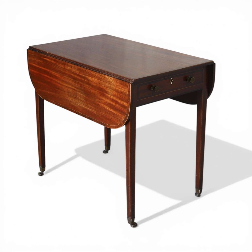 A late 18th-century Sheraton style mahogany Pembroke table with drop leaves, a single drawer, partridge wood crossbanding, and tapered legs on brass castors.