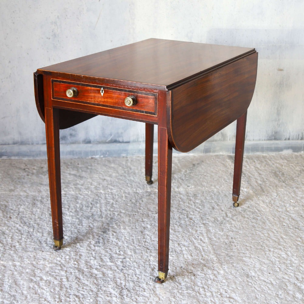 A late 18th-century Sheraton style mahogany Pembroke table with drop leaves, a single drawer, partridge wood crossbanding, and tapered legs on brass castors. View IV