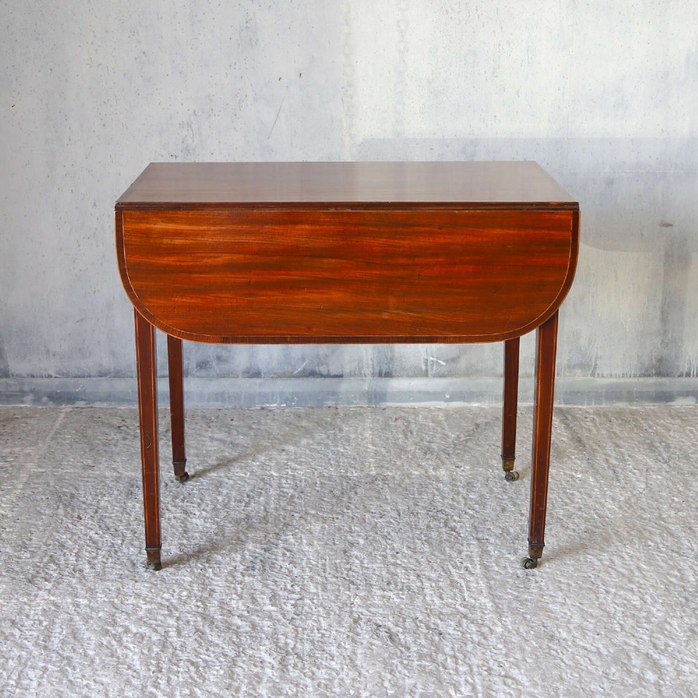 A late 18th-century Sheraton style mahogany Pembroke table with drop leaves, a single drawer, partridge wood crossbanding, and tapered legs on brass castors. View V