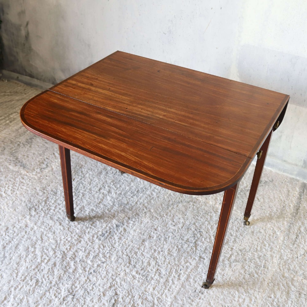 A late 18th-century Sheraton style mahogany Pembroke table with drop leaves, a single drawer, partridge wood crossbanding, and tapered legs on brass castors. View IX