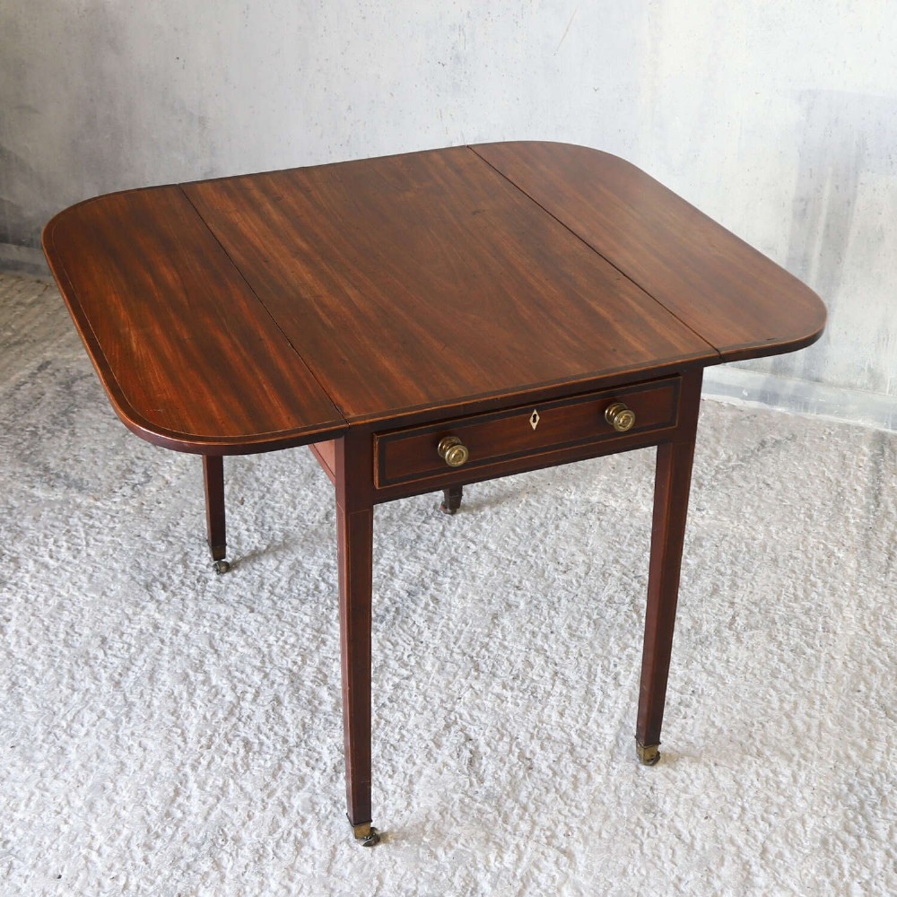 A late 18th-century Sheraton style mahogany Pembroke table with drop leaves, a single drawer, partridge wood crossbanding, and tapered legs on brass castors. View X