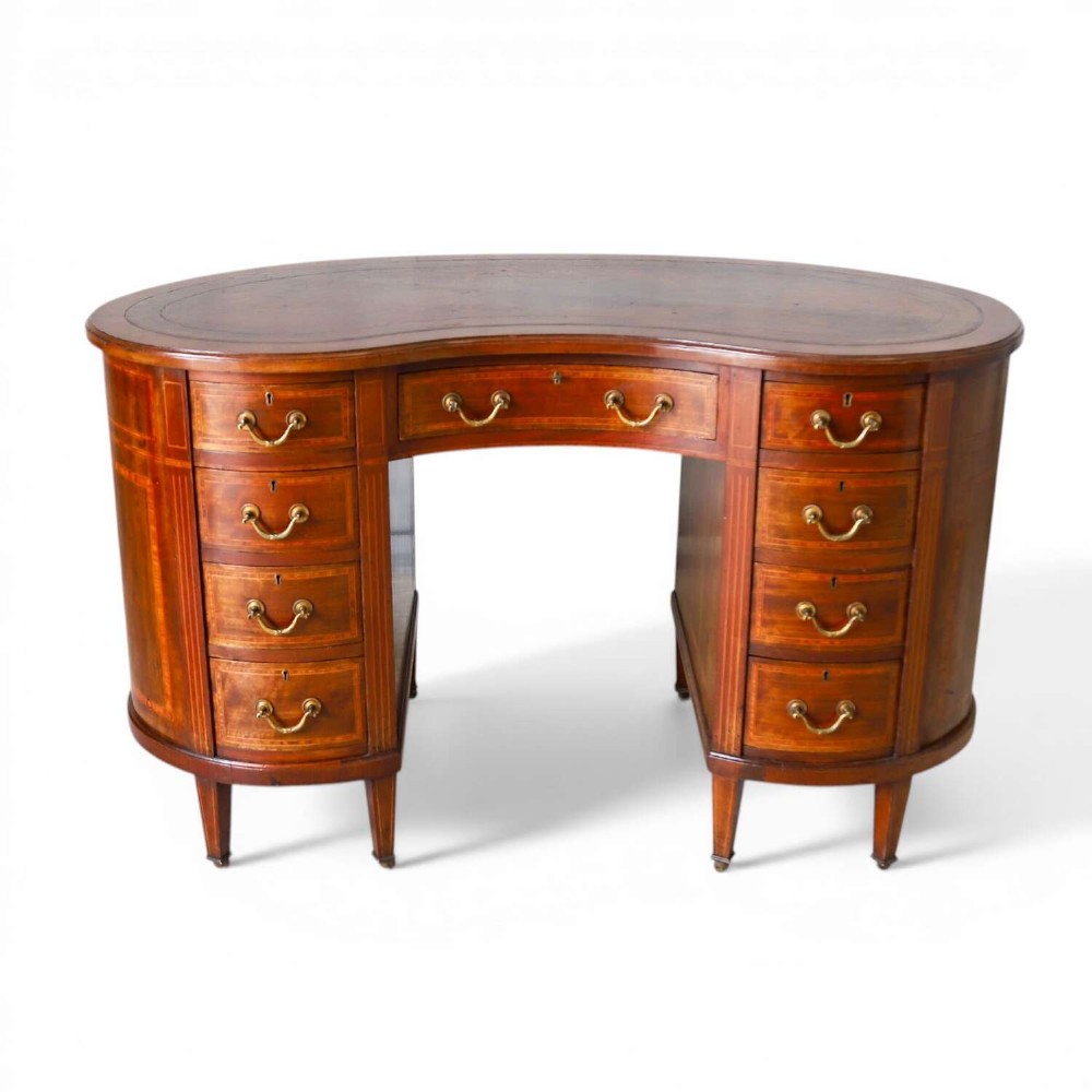 A late eighteenth-century Sheraton Revival mahogany kidney-shaped writing desk featuring a gilt-tooled leather top, nine drawers with brass handles, and line inlay.