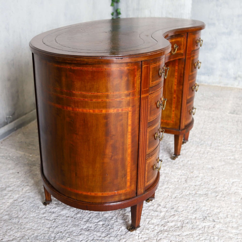 A late eighteenth-century Sheraton Revival mahogany kidney-shaped writing desk featuring a gilt-tooled leather top, nine drawers with brass handles, and line inlay. View II