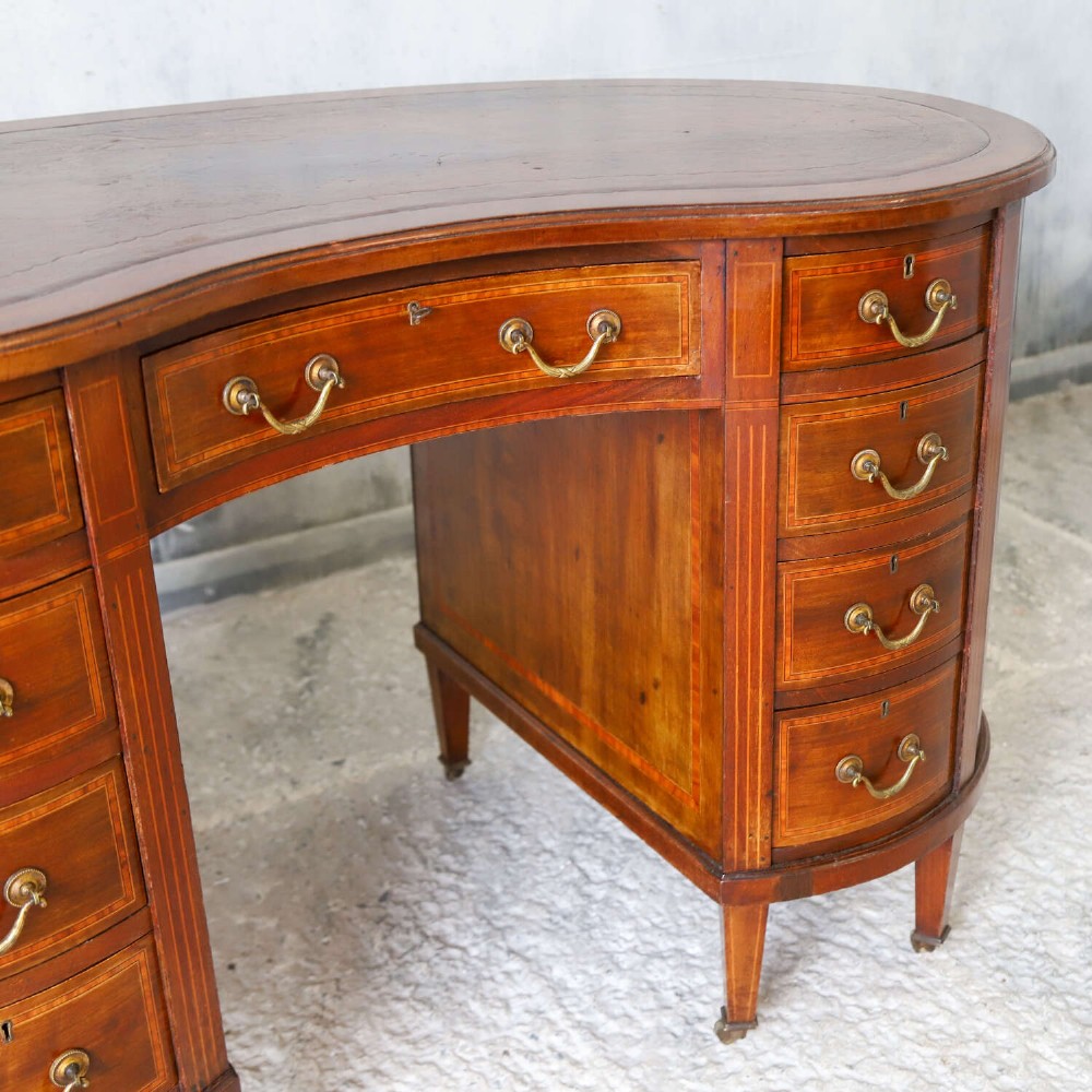 A late eighteenth-century Sheraton Revival mahogany kidney-shaped writing desk featuring a gilt-tooled leather top, nine drawers with brass handles, and line inlay. View VII