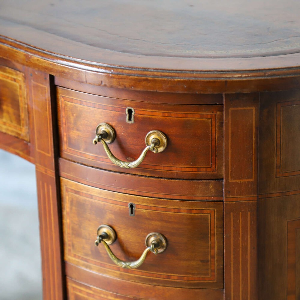 A late eighteenth-century Sheraton Revival mahogany kidney-shaped writing desk featuring a gilt-tooled leather top, nine drawers with brass handles, and line inlay. View XI