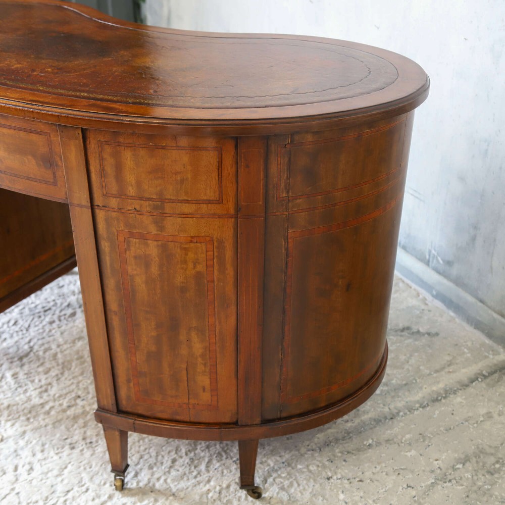 A late eighteenth-century Sheraton Revival mahogany kidney-shaped writing desk featuring a gilt-tooled leather top, nine drawers with brass handles, and line inlay. View XIV