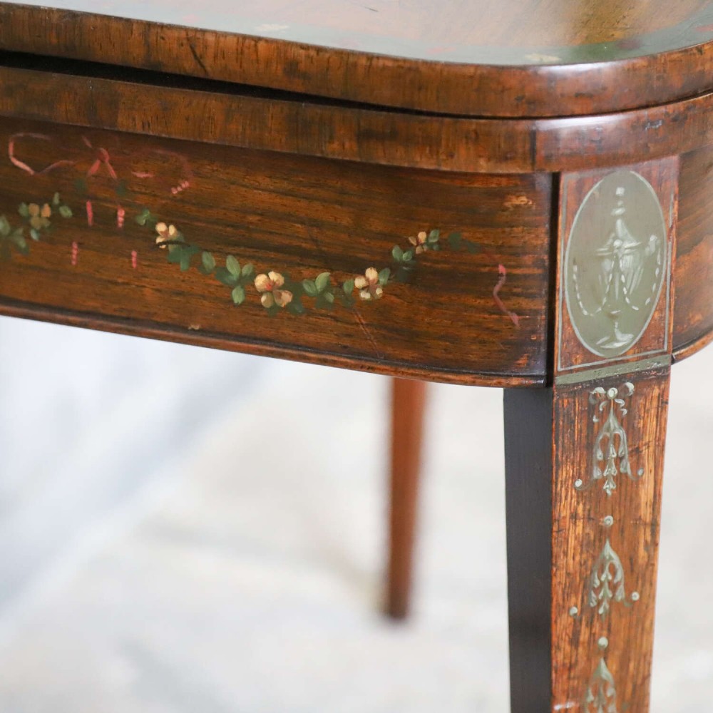 A Regency rosewood card table with a fold-over top, tapered legs, and hand-painted floral garland decoration along the apron. View V