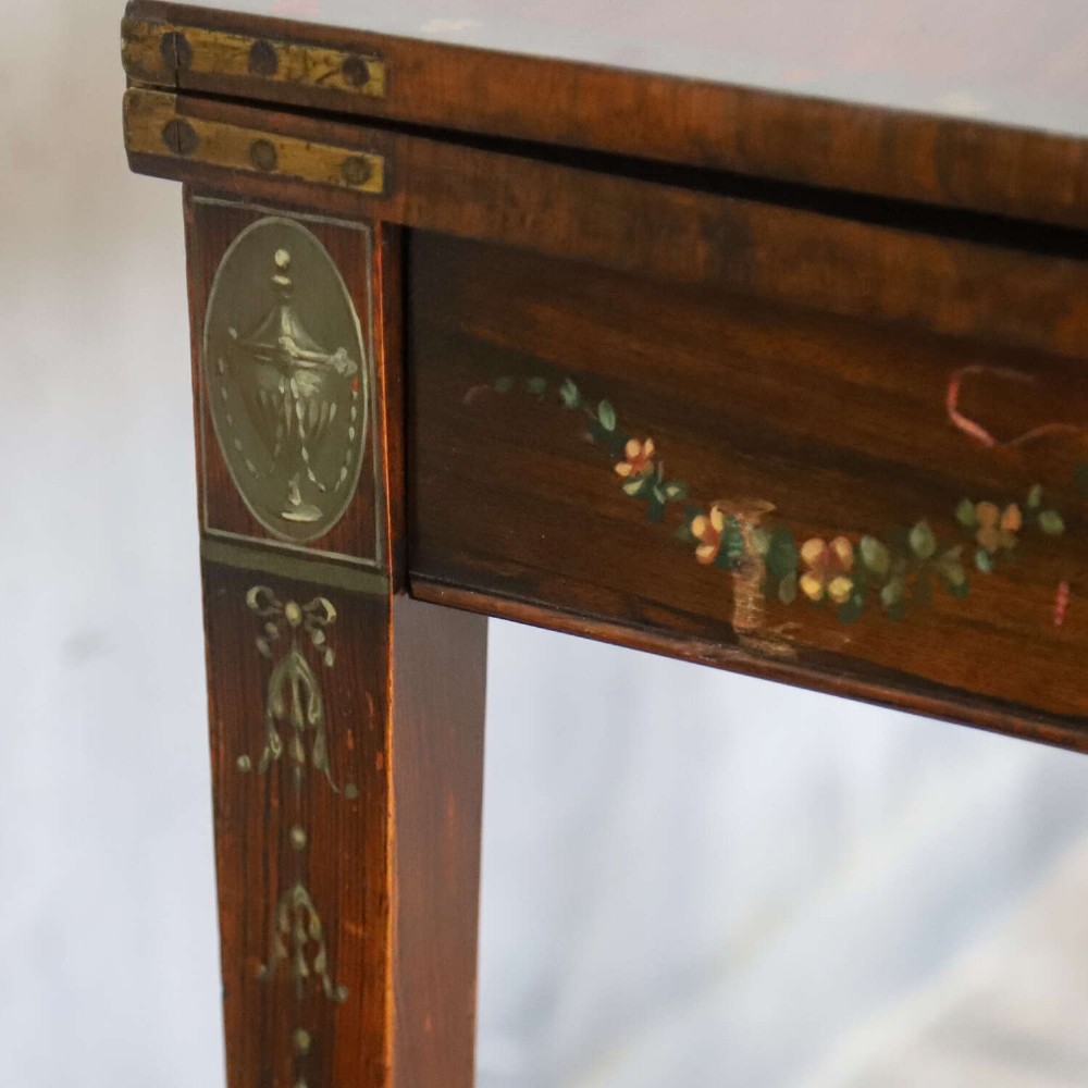 A Regency rosewood card table with a fold-over top, tapered legs, and hand-painted floral garland decoration along the apron. View VI